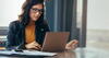 woman wearing glasses working on a laptop 